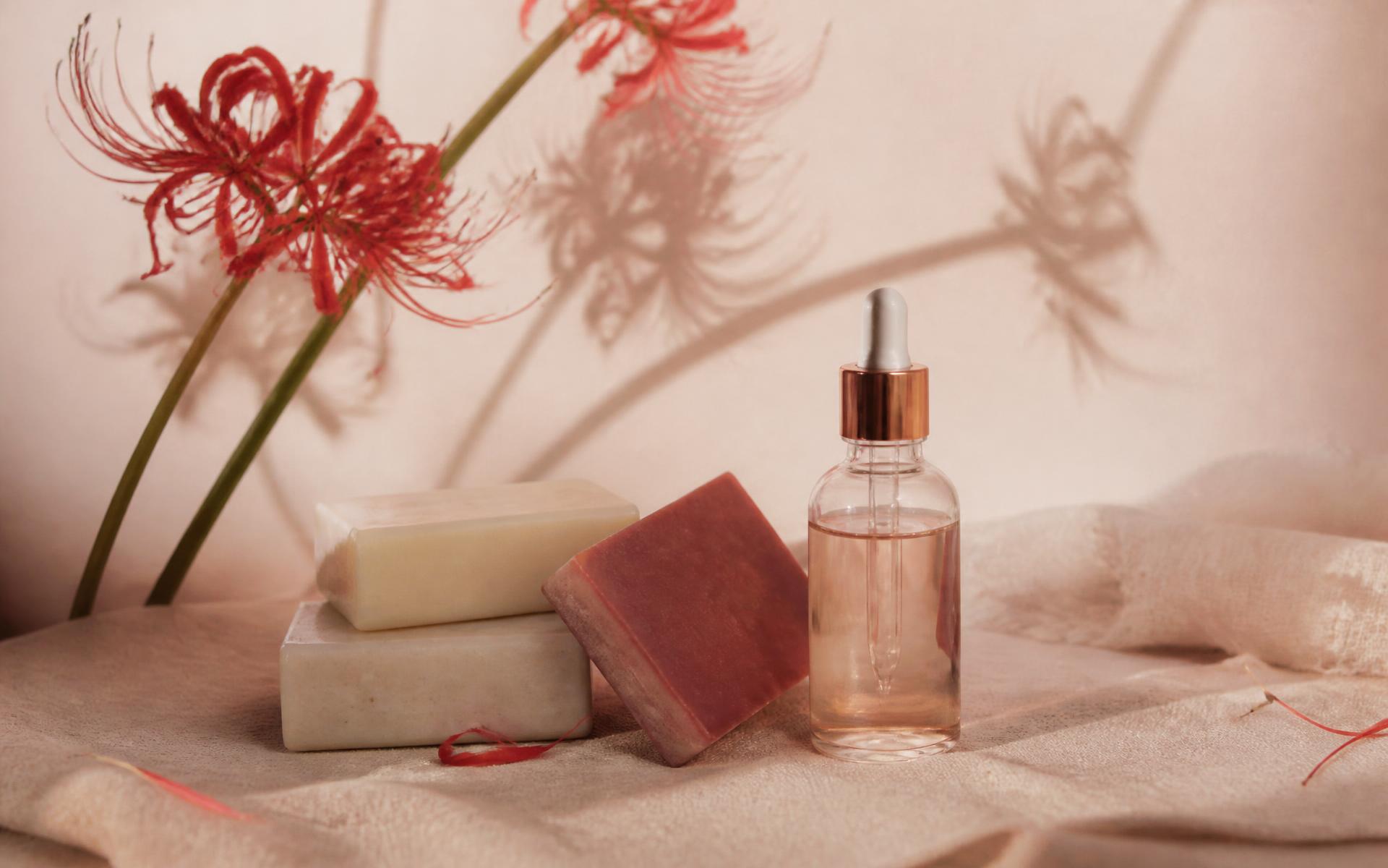 Handmade Lyriora soap bars and a serum bottle beside red spider lily stems